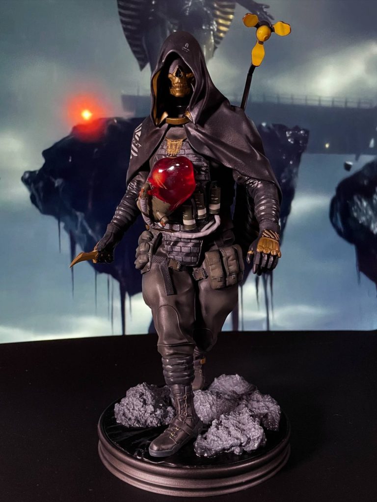 Hand-painted statue inspired by Higgs from Death Stranding, in a hood and gold skull mask, with a curved knife and a red glowing chest piece